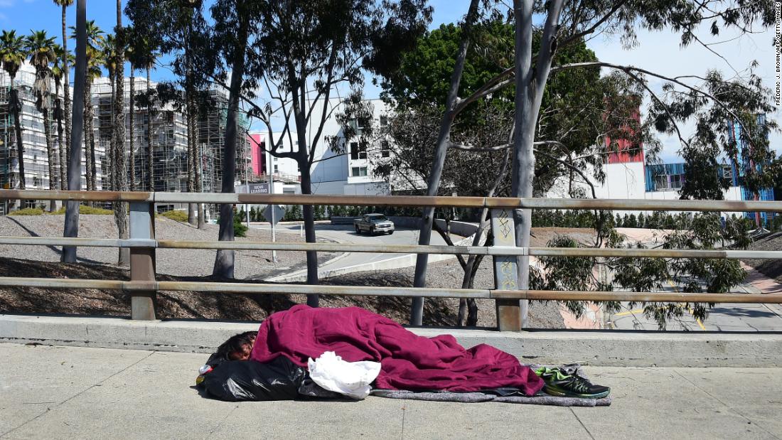 A homeless man sleeps on a sidewalk in Los Angeles on March 10.