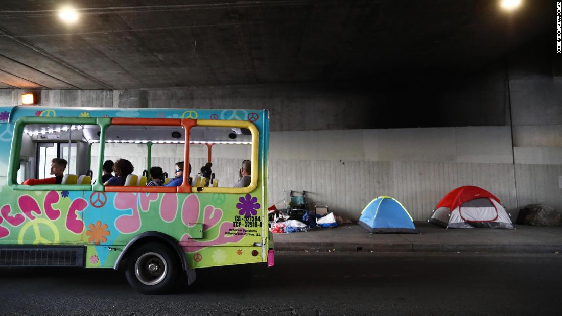 A tour bus passes a homeless encampment located beneath an overpass on June 5.