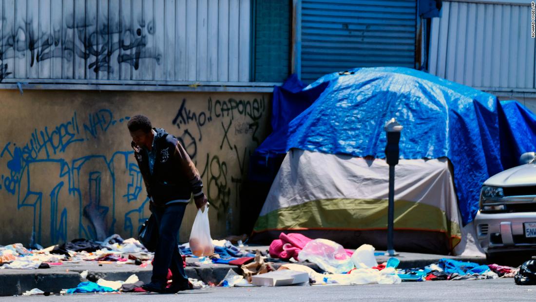 A homeless man walks along a street lined with trash across from a Los Angeles police station on May 30.