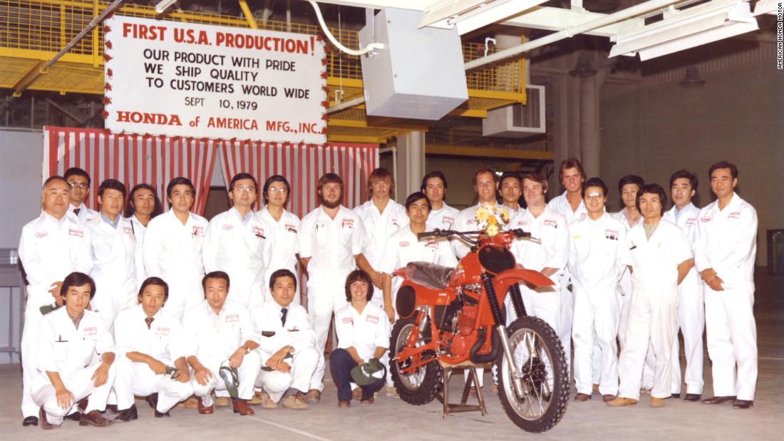 Associates pose alongside the CR250R motorcycle model at Honda&#39;s first motorcycle plant. 