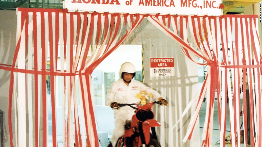 Hot off the assembly production line, a Japanese worker showcases the CR250R motorcycle model at Honda&#39;s Marysville plant.