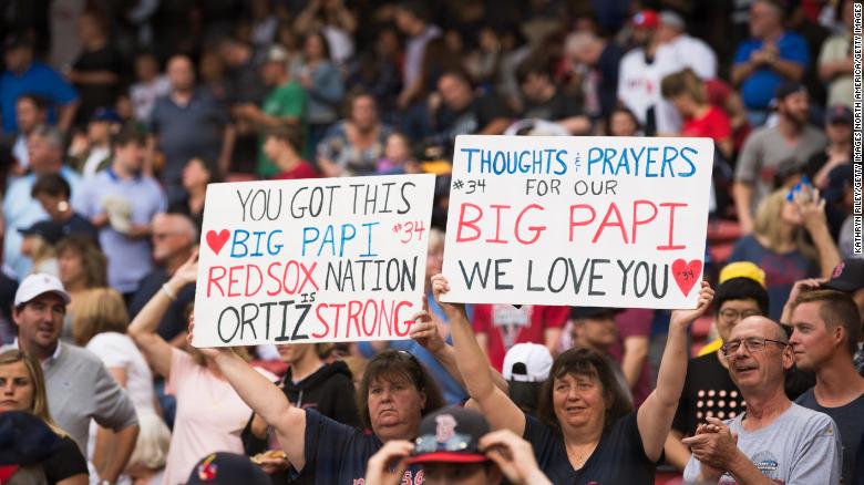 Fans hold up signs showing support for former Red Sox player David Ortiz before the start of the game against the Texas Rangers at Fenway Park on Monday. 