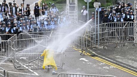 Police officers use a water canon on a lone protester near the government headquarters in Hong Kong on June 12, 2019.