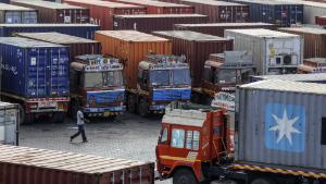 A man walks past container trucks sitting parked near the Jawaharlal Nehru Port, operated by Jawaharlal Nehru Port Trust (JNPT), in Navi Mumbai, Maharashtra, India, on Saturday, May 25, 2019. President Donald Trump opened another potential front in his trade war on May 31, terminating India's designation as a developing nation and thereby eliminating an exception that allowed the country to export nearly 2,000 products to the U.S. duty-free. Photographer: Dhiraj Singh/Bloomberg via Getty Images