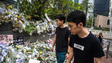 Hong Kong pro-democracy activist Joshua Wong (left), who was just released from jail, walks past flower tributes at a makeshift memorial site for a protester who fell to his death while hanging banners against a controversial extradition law proposal on June 15, in Hong Kong on June 17, 2019.