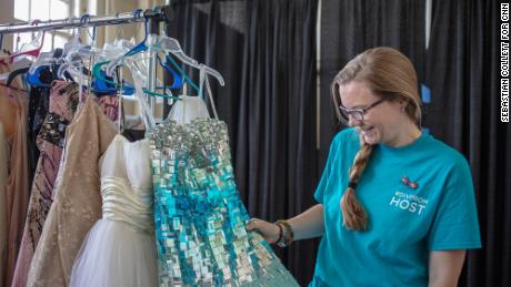 Aly Chapman looks through the garments in a dressing room filled with spare dresses and tuxedos for students to borrow.