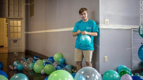 Fox strings together balloons to hang above the entryway into the prom.