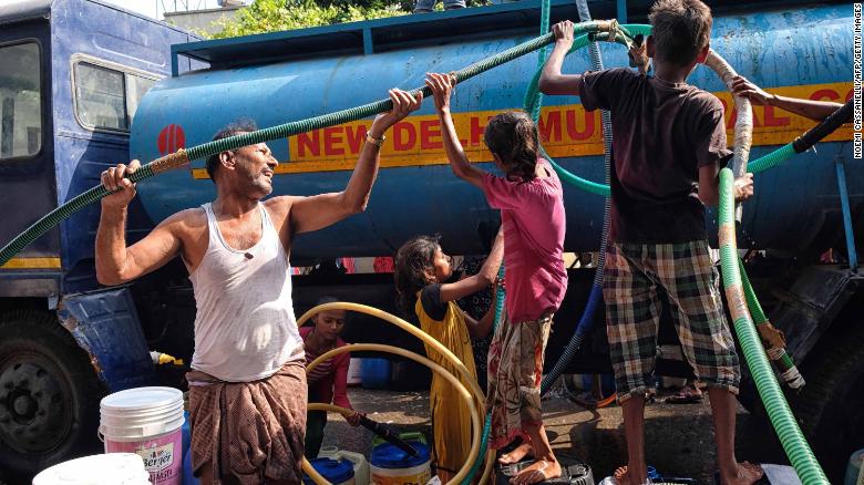Indian residents use hoses to collect drinking water from a tanker in Sanjay, New Delhi.