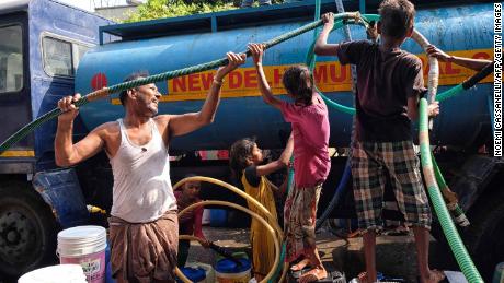 Indian residents use hoses to collect drinking water from a tanker in Sanjay, New Delhi.