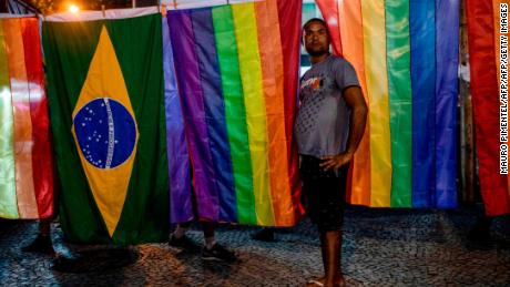 A vendor sells LGBT and Brazil flags during the concentration of a national strike protest called by unions and students against the Brazilian President Jair Bolsonaro's pension reform in Rio de Janeiro, Brazil, on June 14, 2019. - Bolsonaro's ambitious overhaul of Brazil's pension system -- which he has warned will bankrupt the country if his proposal is not approved -- is seen as key to getting a pipeline of economic policies through Congress. (Photo by MAURO PIMENTEL / AFP)        (Photo credit should read MAURO PIMENTEL/AFP/Getty Images)