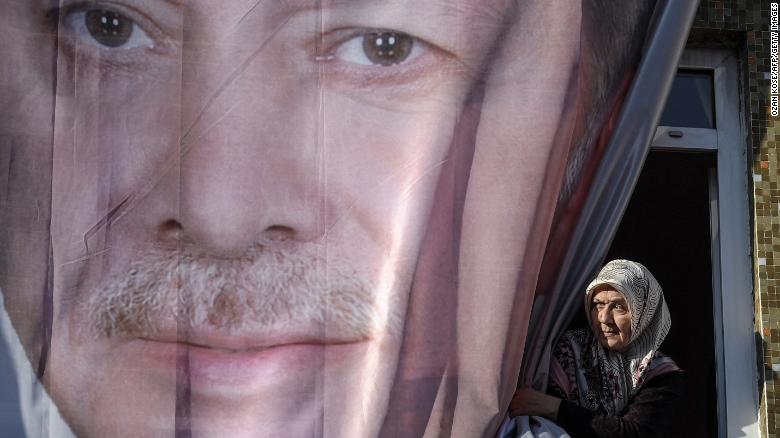 A woman peers out from behind a giant poster of Erdoğan during a March rally in Kasımpaşa.