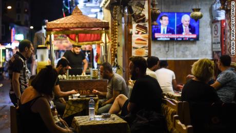 At an Istanbul café, people watch a live TV debate between Istanbul&#39;s main mayoral candidates.