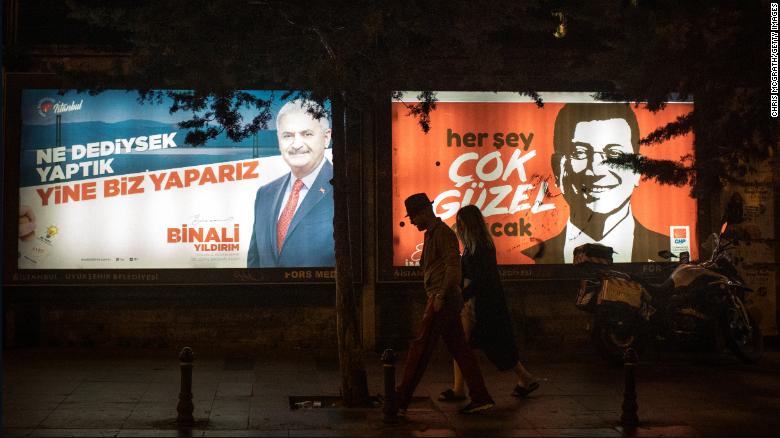 People walk past Yıldırım and İmamoğlu election posters amid campaigning for the rerun.