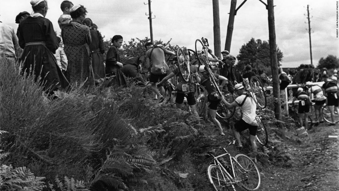 When the route was changed during the 1939 Tour, Capa was there to show the cyclists carrying their bikes over some brush — and to note the curious eyes of local residents. 