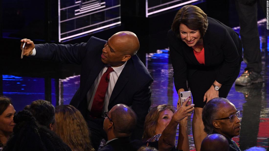 Booker and Klobuchar take selfies with supporters after Wednesday&#39;s debate.