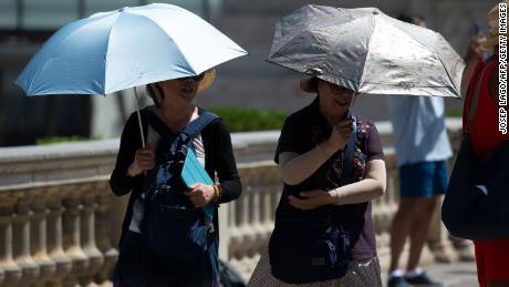 Tourists walk under umbrellas to protect themselves from the sun on a warm summer day in Barcelona on June 28.