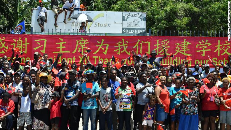 People in Papua New Guinea gather at the roadside to welcome China's President Xi Jinping in Port Moresby on November 16, 2018, ahead of the Asia-Pacific Economic Cooperation (APEC) Summit. A banner thanks Xi for building their local school. 