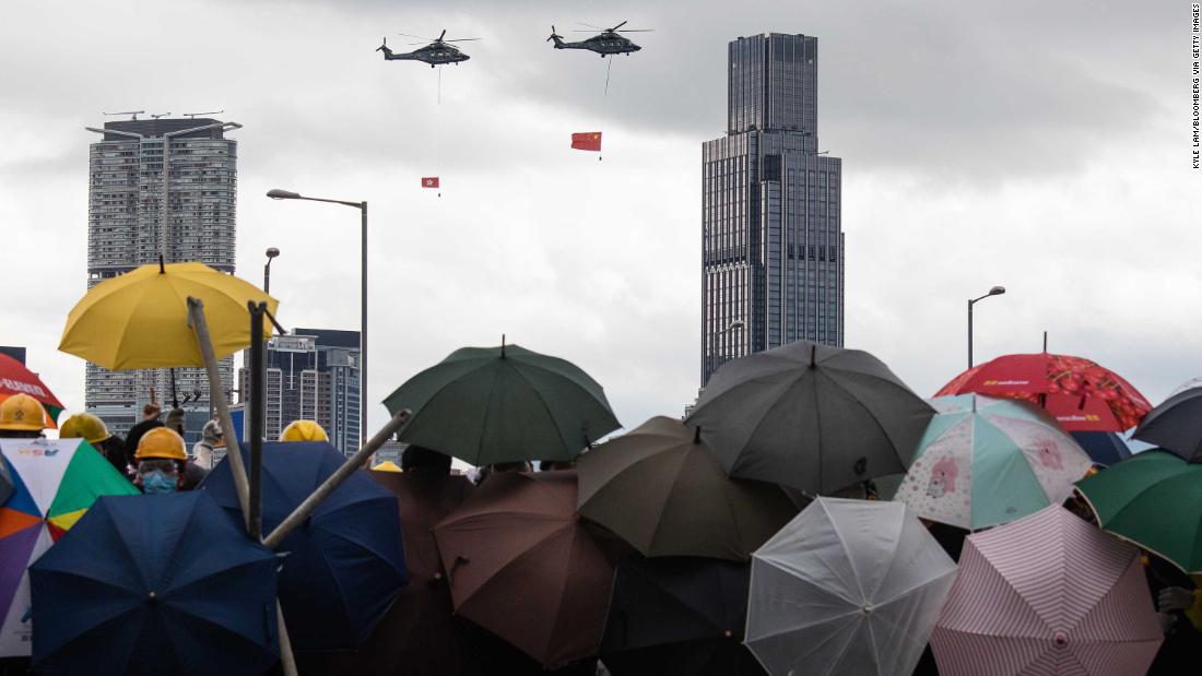 Helicopters carrying the flags of China and Hong Kong fly over demonstrators on July 1.