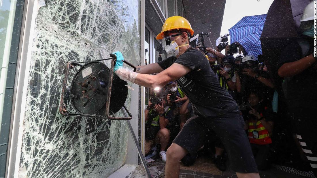 A protester smashes a window of the Legislative Council building.