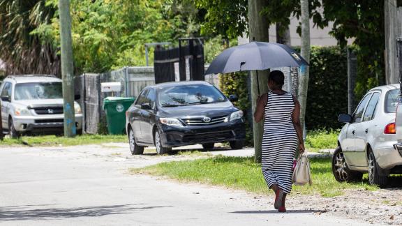 A woman uses an umbrella for shade as she walks on a hot day in Miami.