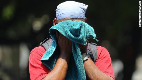 An Indian man uses a towel to wipe the sweat on his face on a hot and humid summer day in Hyderabad, India, on June 3, 2019. 