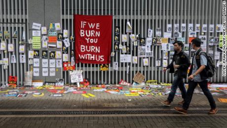 People walk past signs and posters outside the government headquarters in Hong Kong on July 2.