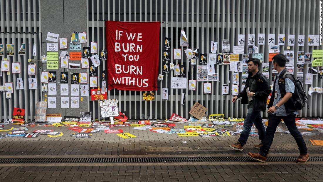 People walk past signs and posters outside the government headquarters in Hong Kong on July 2.