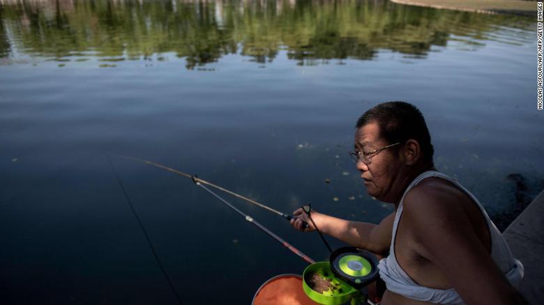 A man sports a so-called Beijing bikini as he fishes by Houhai Lake in Beijing on July 1, 2019. 