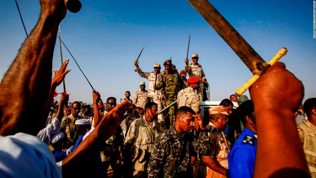 Mohamed Hamdan Dagalo, deputy head of Sudan&#39;s ruling Transitional Military Council (TMC) and commander of the Rapid Support Forces (RSF) paramilitaries, center right, waves a baton as he rides through supporters in Qarri, north of Khartoum, on June 15.