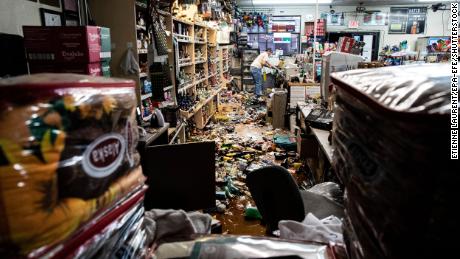 An employee stands behind the counter amid fallen bottles at a gas station and liquor store in Ridgecrest, California, on July 6, 2019.