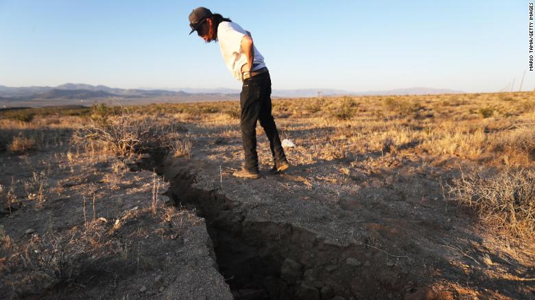 RIDGECREST, CALIFORNIA - JULY 04: A local resident inspects a crack in the earth after a 6.4 magnitude earthquake struck the area on July 4, 2019 near Ridgecrest, California. The earthquake was the largest to strike Southern California in 20 years with the epicenter located in a remote area of the Mojave Desert. The temblor was felt by residents across much of Southern California. (Photo by Mario Tama/Getty Images)