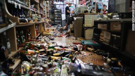 An employee works at the cash register at Eastridge Market, near broken bottles scattered on the floor, following a 7.1 magnitude earthquake, on July 6 in Ridgecrest, California.