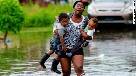 Terrian Jones reacts as she feels something moving in the water at her feet as she carries Drew and Chance Furlough to their mother on Belfast Street in New Orleans during flooding from a storm in the Gulf Mexico that dumped lots of rain Wednesday, July 10, 2019. (AP Photo/Matthew Hinton)