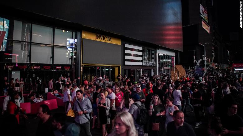 People walk along a dark street near Times Square. 