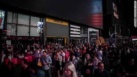 People walk along a dark street near Times Square area. 