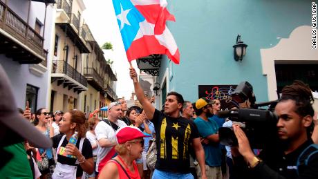 Crowds flooded the streets of Old San Juan carrying Puerto Rican flags and signs that read &quot;Ricky Resign&quot; in Spanish.