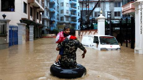 A member of Nepalese army carrying a child walks along the flooded colony in Kathmandu, Nepal on July 12, 2019. 