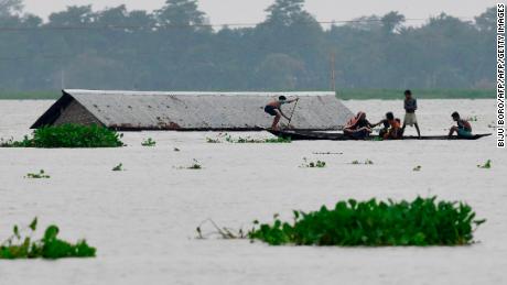 Villagers travel on a boat near a submerged house in the Morigaon district of India&#39;s Assam state on July 15, 2019.