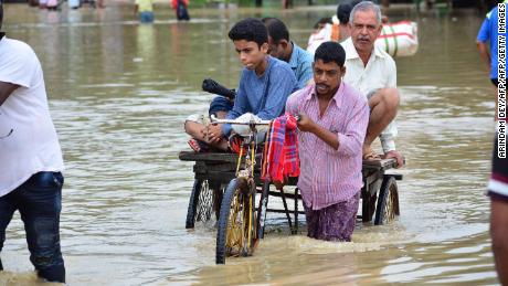 An Indian rickshaw puller transports commuters on a flooded street in the Indian state of Tripura, on July 14, 2019.