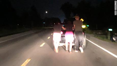 Aeron McQuillin, Bailey Campbell, Billy Tarbett push a stranded motorist&#39;s car home.