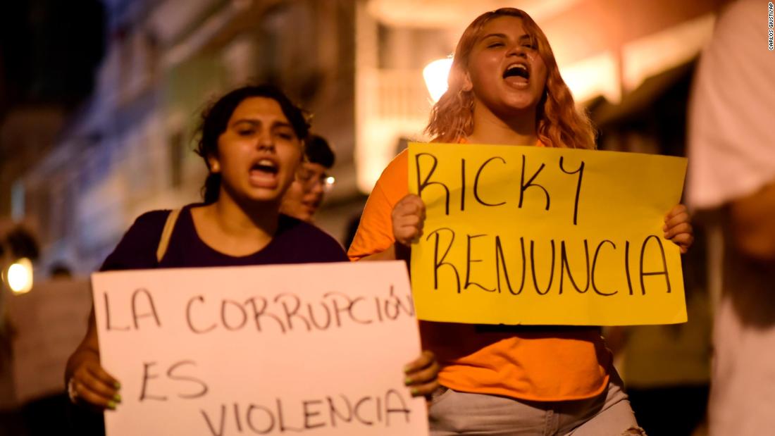 Demonstrators hold signs that say &quot;Corruption is violence&quot; and &quot;Ricky resign&quot; while protesting near the executive mansion on Thursday, July 11.