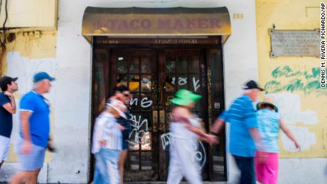 Tourists walk past a closed taco restaurant in San Juan.