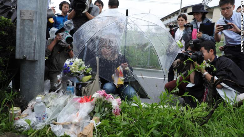 A woman pays her respects next to flowers and tributes laid at the scene of the Kyoto Animation fire.