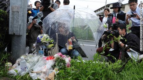 A woman pays her respects next to flowers and tributes laid at the scene of the Kyoto Animation fire.