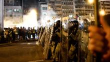Riot police are seen as tear gas is fired after a march against a controversial extradition bill in Hong Kong on July 21, 2019. - Masked protesters daubed the walls of China's office in Hong Kong with eggs and graffiti on the night of July 21 following another massive rally, focusing anger towards the embodiment of Beijing's rule with no end in sight to the turmoil engulfing the finance hub. (Photo by Anthony WALLACE / AFP)        (Photo credit should read ANTHONY WALLACE/AFP/Getty Images)