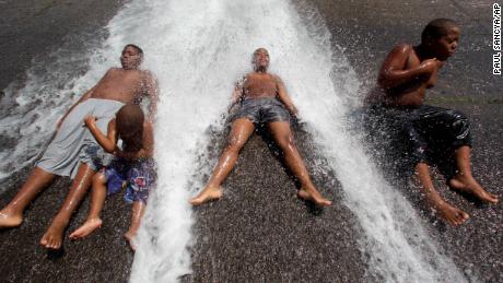 Kids play in an open fire hydrant during the heat wave in Detroit.