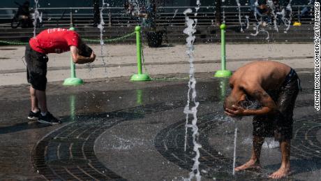 People cool off in a splash pad at a park in New York.