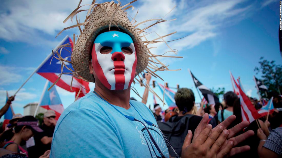 A masked man protests in San Juan.