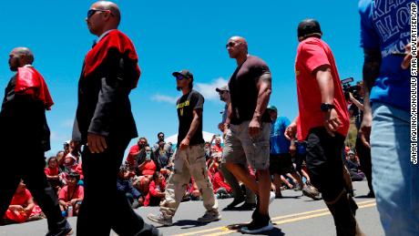 Actor Dwayne &quot;The Rock&quot; Johnson, third from right, walks with TMT opposition leader Kaho&#39;okahi Kanuha, third from left, while being accompanied by the Royal Order of Kamehameha I during a visit to the protests against the TMT telescope, Wednesday, July 24, 2019, at the base of Mauna Kea on Hawaii Island. (Jamm Aquino/Honolulu Star-Advertiser via AP)