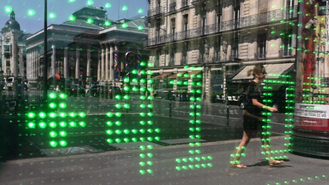 A woman in Paris walks past a window reflecting a temperature of 41 degrees Celsius (105.8 degrees Fahrenheit) on Thursday, July 25.